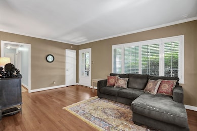 Living room featuring wood finished floors, ornamental molding, and baseboards