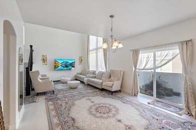 Living room featuring wood finished floors, a chandelier, and arched walkways