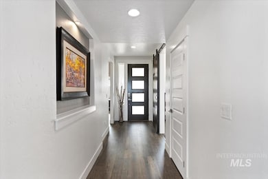 Doorway featuring a barn door, wood finished floors, a textured ceiling, and recessed lighting