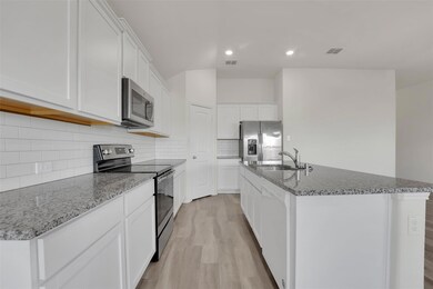 Kitchen featuring sink, light hardwood / wood-style floors, a center island with sink, white cabinets, and appliances with stainless steel finishes