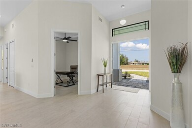 Entryway with ceiling fan, light hardwood / wood-style floors, and a towering ceiling