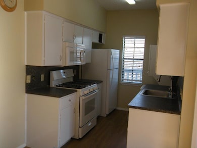 Kitchen with white cabinets, a sink, dark counter