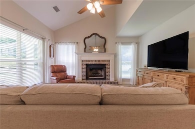 Living area with ceiling fan, a brick fireplace, and high vaulted ceiling
