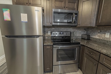 Kitchen featuring stainless steel appliances, dark
