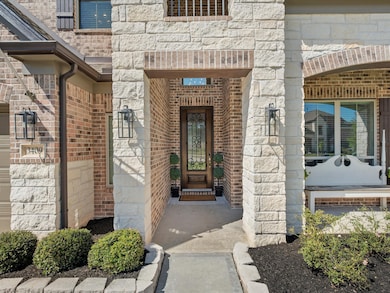 Built with the Premium Stone & Brick Elevation, relax on the covered Front Patio adorned with an 8' Mahogany Wood Front Door.