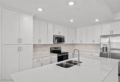 Kitchen with a sink, stainless steel appliances, light countertops, white cabinets, and backsplash
