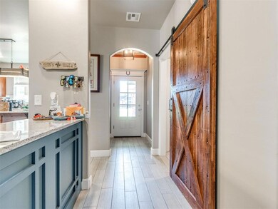 Entryway with a barn door, arched walkways, and wood finished floors