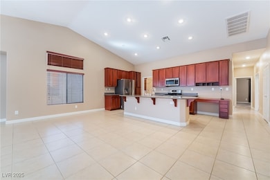 Kitchen featuring a breakfast bar, dark brown cabinets, light tile patterned floors, recessed lighting, and high vaulted ceiling
