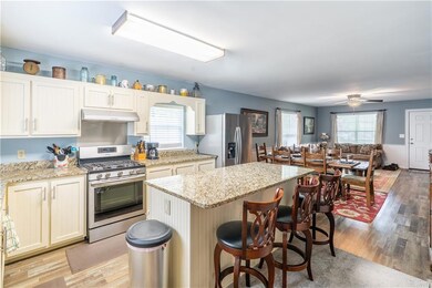 Kitchen with appliances with stainless steel finishes, a kitchen island, light wood finished floors, open floor plan, and a breakfast bar area