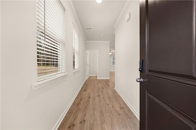 Corridor featuring ornamental molding and light wood-type flooring