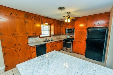 Kitchen featuring black appliances, sink, tasteful