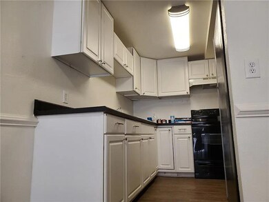Kitchen featuring white cabinetry, black electric range, dark wood finished floors, and dark countertops