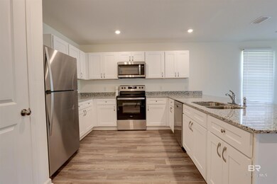 Kitchen featuring appliances with stainless steel finishes, light hardwood / wood-style flooring, white cabinetry, and kitchen peninsula