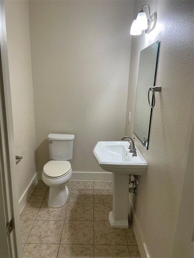 Half bath featuring toilet, baseboards, tile patt