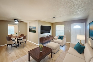 Living room with light wood-style flooring, a textured ceiling, plenty of natural light, and ceiling fan