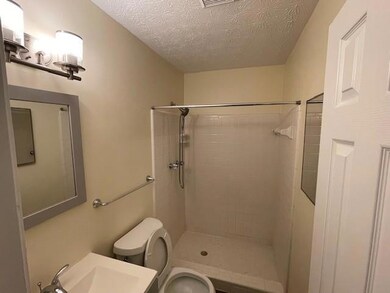 Bathroom with tiled shower and a textured ceiling