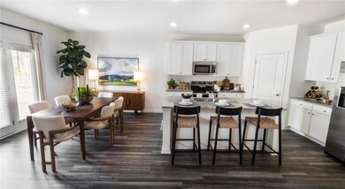 Kitchen with white cabinetry, dark hardwood / wood