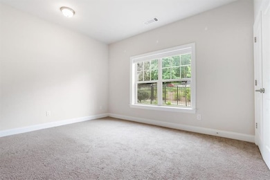 Carpeted spare room featuring baseboards