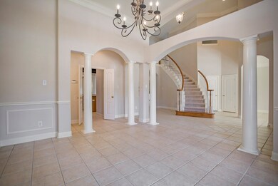 The formal dining room also features a high ceiling, crown molding, Tuscan columns and a lovely chandelier.