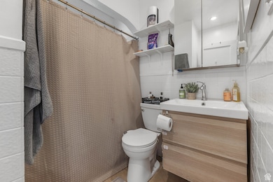 Full bathroom with tile walls, vanity, backsplash, and curtained shower