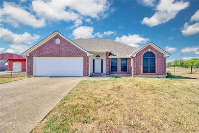Single story home featuring roof with shingles, concrete driveway, brick siding, and an attached garage