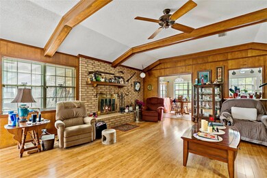 Living room with a fireplace, ceiling fan, vaulted