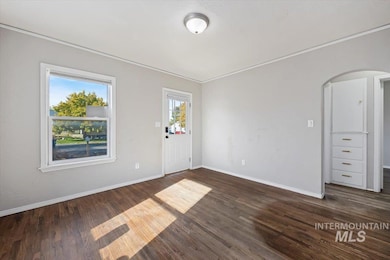 Foyer entrance with dark wood-type flooring, crown molding, and arched walkways