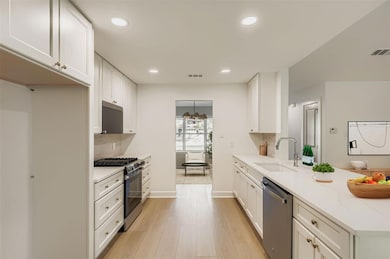 Kitchen with white cabinetry, recessed lighting, appliances with stainless steel finishes, light wood-style floors, and light stone countertops