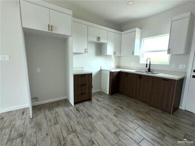 Kitchen featuring dark brown cabinets, sink, white cabinets, and light hardwood / wood-style floors
