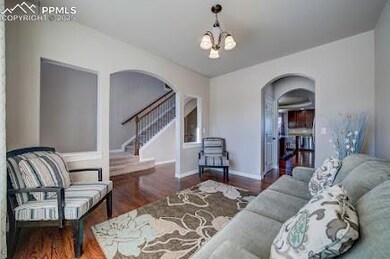 Living area featuring wood finished floors, stairway, arched walkways, baseboards, and a chandelier
