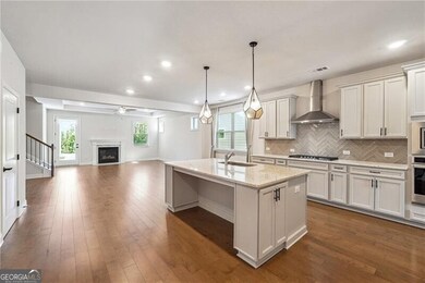 Kitchen featuring wall chimney range hood, open fl