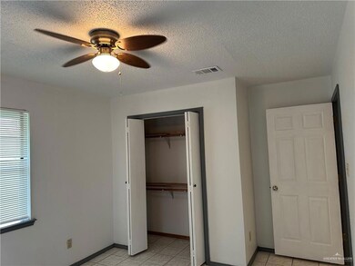 Unfurnished bedroom with a closet, a textured ceiling, light tile patterned flooring, multiple windows, and ceiling fan