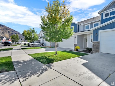 View of grassy yard with a residential view, concrete driveway, and a garage