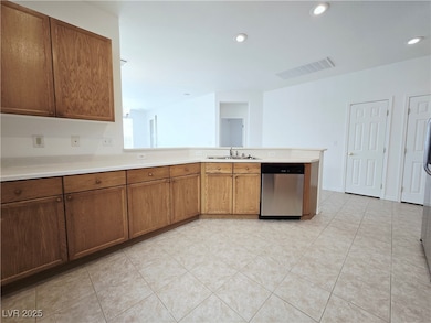 Kitchen with brown cabinetry, dishwasher, light countertops, light tile patterned floors, and recessed lighting