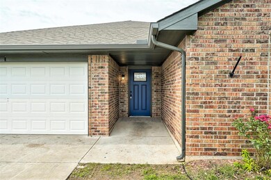 Doorway to property featuring an attached garage, brick siding, a shingled roof, and driveway