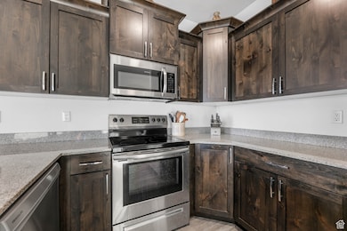 Kitchen featuring stainless steel appliances, open floor plan, staggered knotty alder cabinets, granite countertops, and laminate floors.