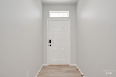 Doorway with wood finished floors and baseboards