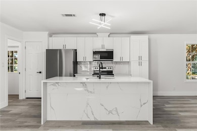 modern kitchen featuring brand-new appliances, new cabinets, new countertops, and stylish black fixtures.
