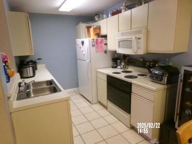 Kitchen featuring white appliances, cream cabinets