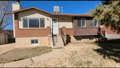 View of front of house with a chimney, brick siding, a storage unit, and a front lawn