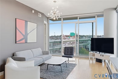 Living room featuring a wall of windows, light wood-type flooring, and a chandelier