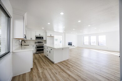 Kitchen featuring appliances with stainless steel finishes, white cabinets, light wood-style flooring, a center island, and recessed lighting