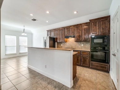 Kitchen featuring a kitchen island, tasteful backsplash, light tile patterned floors, dark brown cabinetry, and black appliances
