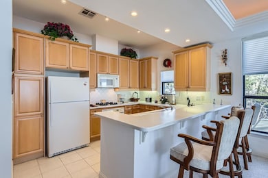 Kitchen with white appliances, visible vents, a p