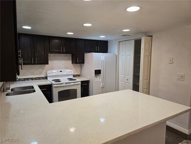Kitchen with white appliances, dark cabinets, ligh