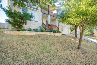 View of front of home with a balcony, a garage, driveway, stone siding, and a front yard