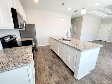 Kitchen featuring white cabinetry, stainless steel electric range, black microwave, an island with sink, and recessed lighting