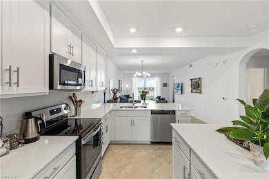 Kitchen with appliances with stainless steel finishes, white cabinetry, hanging light fixtures, a peninsula, and recessed lighting