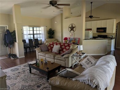 Living room with a ceiling fan, dark wood-style flooring, and high vaulted ceiling