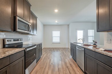 Kitchen with light style floors, light stone counters, backsplash, and stainless steel appliances
